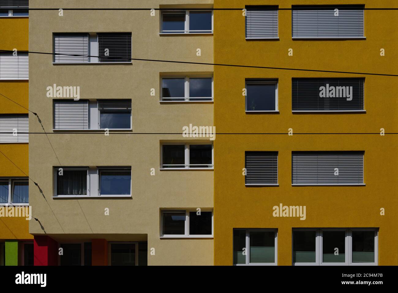 Außenansicht von vorne, typische Fassade der modernen Residenz oder Wohnung in der Stadt Europa mit rechteckigen Fenstern und verschiedenen Schatten der gelben Wand. Stockfoto