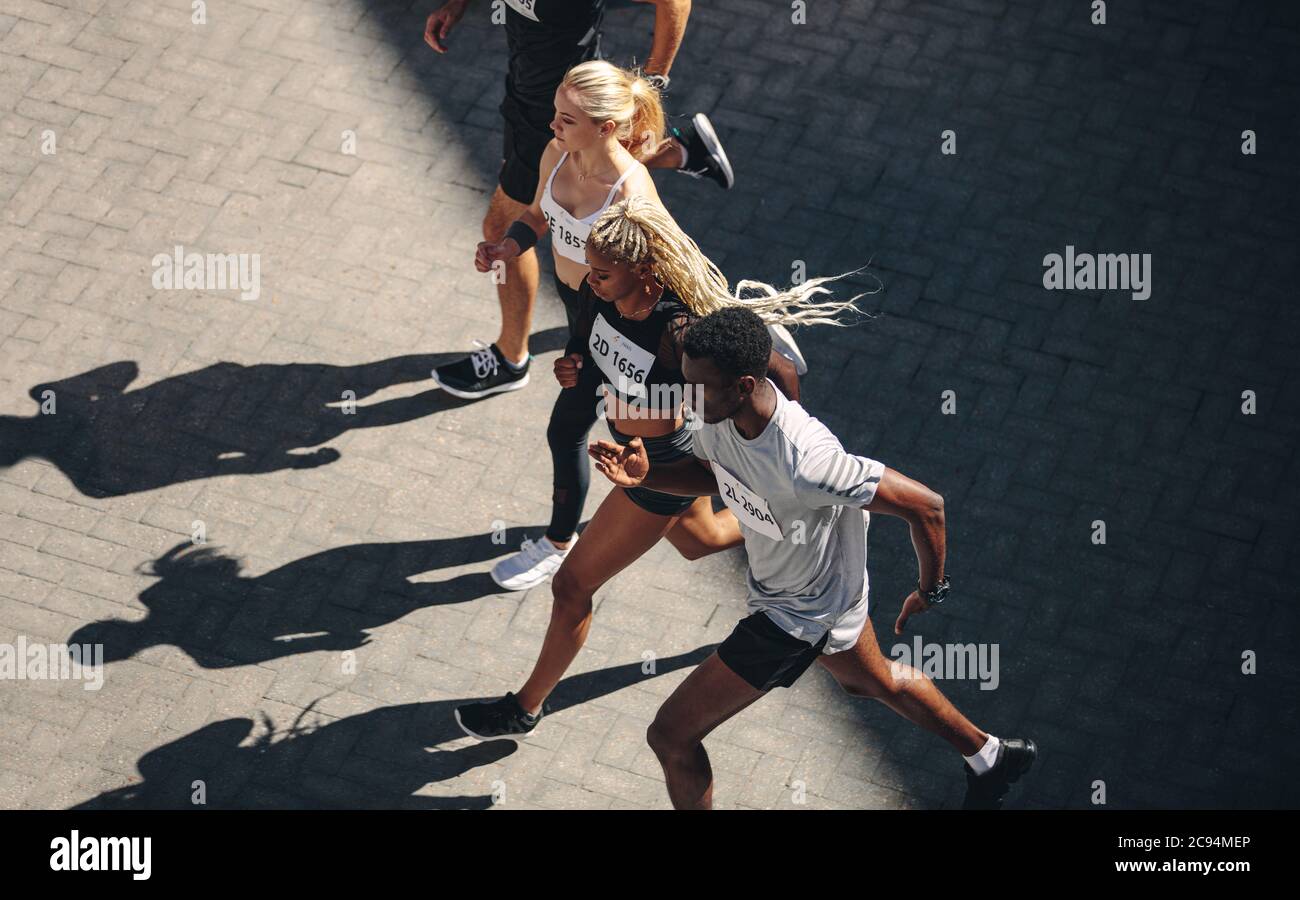 Multiethnische Gruppe von Menschen, die zusammen laufen. Draufsicht auf die Mitglieder des Laufclubs, die gemeinsam in der Stadt trainieren. Stockfoto