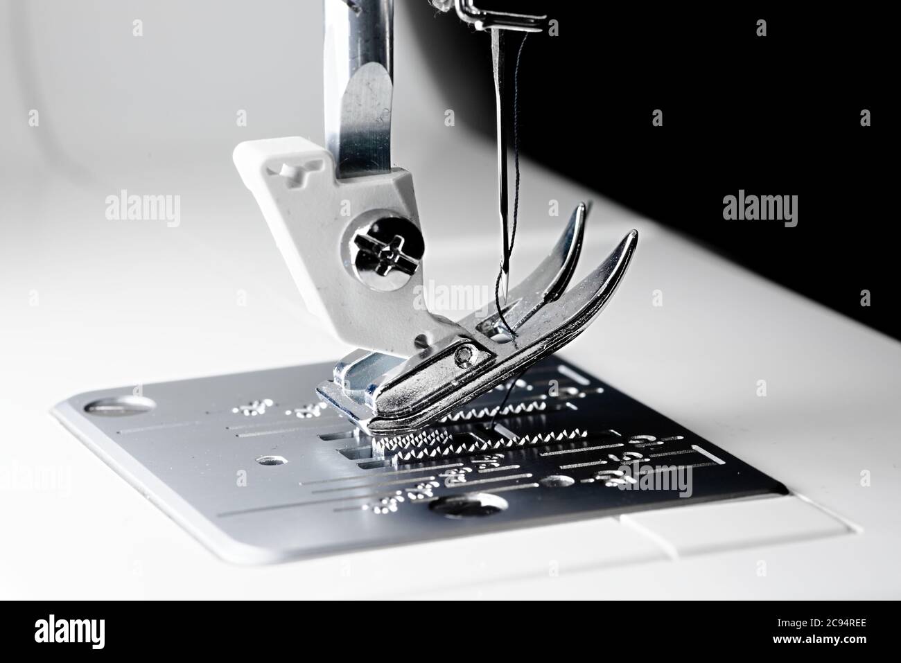 3 - Schließen Makro Nähmaschinenbild mit selektivem Fokus zeigt Nadel, Faden, Presser Fuß, Futterhunde und Kehlplatte. Stockfoto