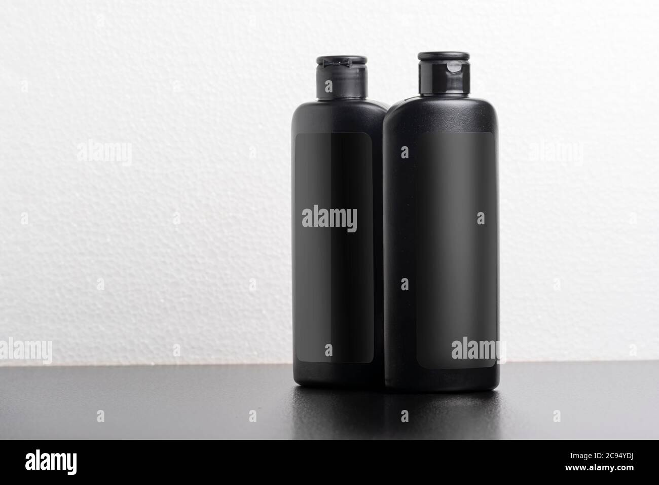 Schwarze Haar Shampoo-Flaschen vor hellgrauem Hintergrund, bearbeitbare Modell-up-Serie Vorlage bereit für Ihr Design, Auswahlpfad enthalten. Stockfoto