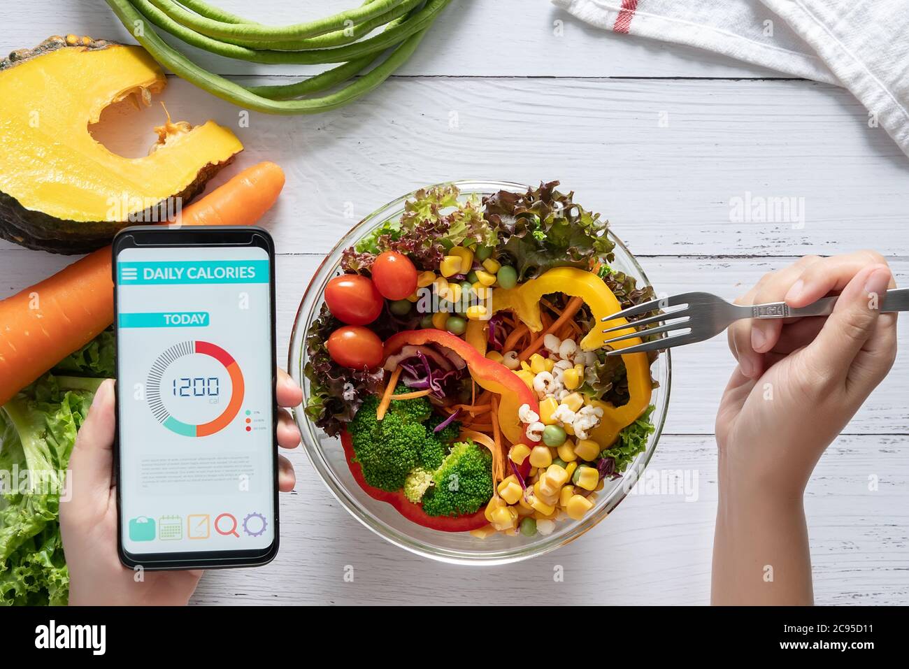 Kalorienzählen, Ernährung, Kontrolle der Lebensmittel und Gewichtsverlust Konzept. Kalorienzähler Anwendung auf Smartphone-Bildschirm am Esstisch mit Salat, Obst Stockfoto