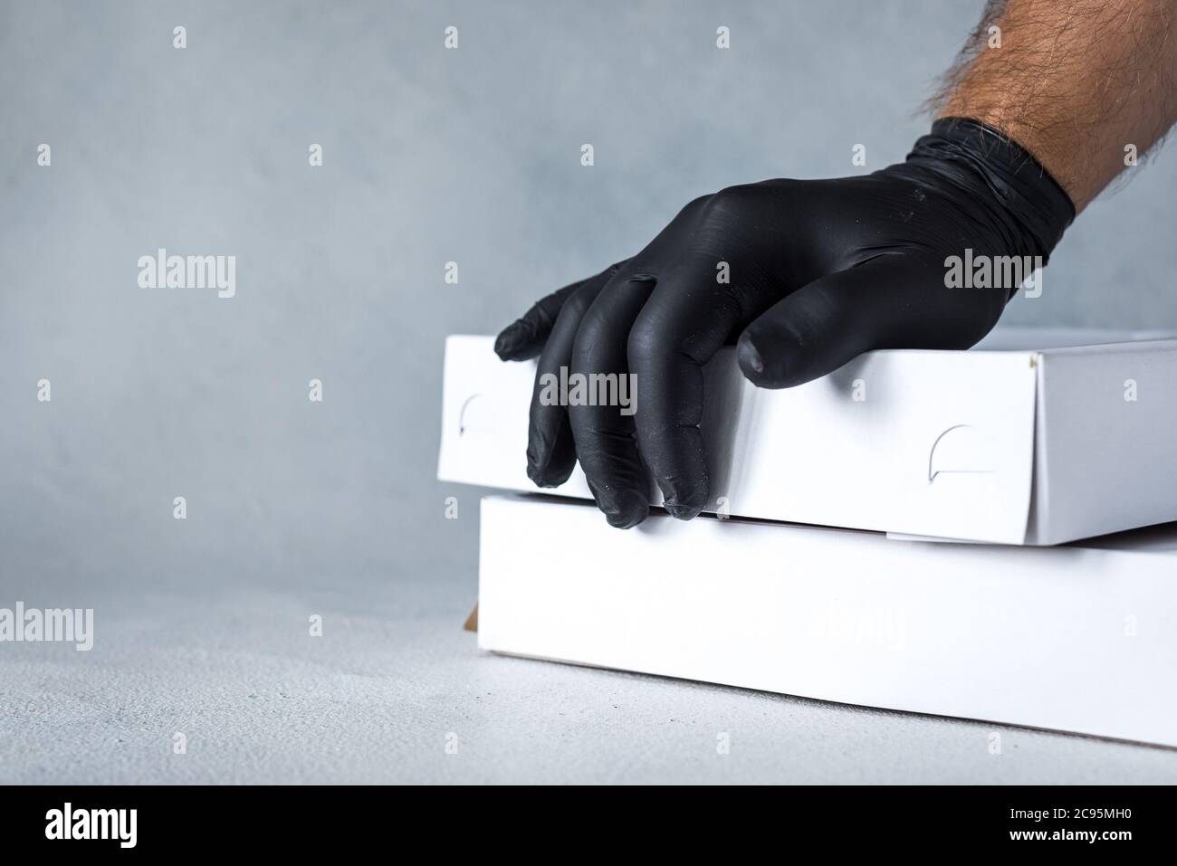 Lieferung nach Hause, Online-Bestellung. Gummihandschuhe mit einer Box, mit einem Paket in den Händen. Lebensmittel- und Lebensmittelzustellung während der Quarantäne Stockfoto