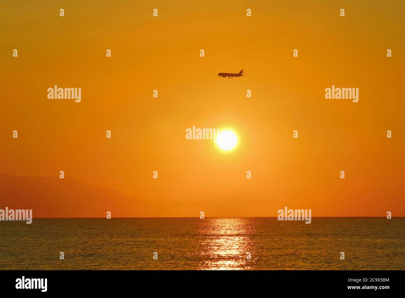 Sonnenaufgang über dem Meer. Flugzeug kommt an Land. Stockfoto