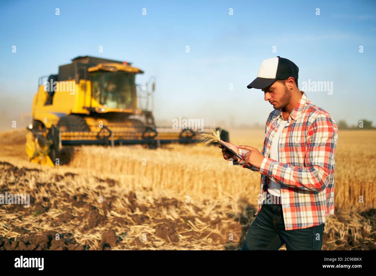 Präzisionslandwirtschaft. Landwirt hält Tablet für Mähdrescher Führung und Steuerung mit modernen Automatisierungssystem. Agronom mit Online-Daten Stockfoto