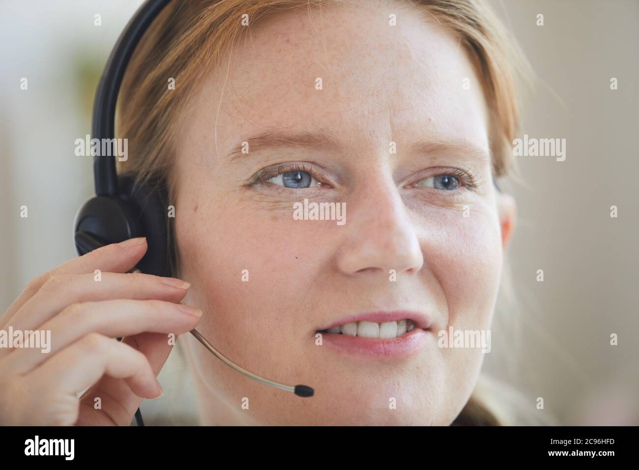Nahaufnahme einer rothaarigen Frau im Headset, die mit Kunden im Büro zusammenarbeitet Stockfoto
