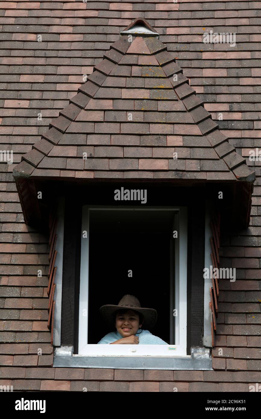 Junge schaut aus einem Fenster in Eure, Frankreich. Stockfoto