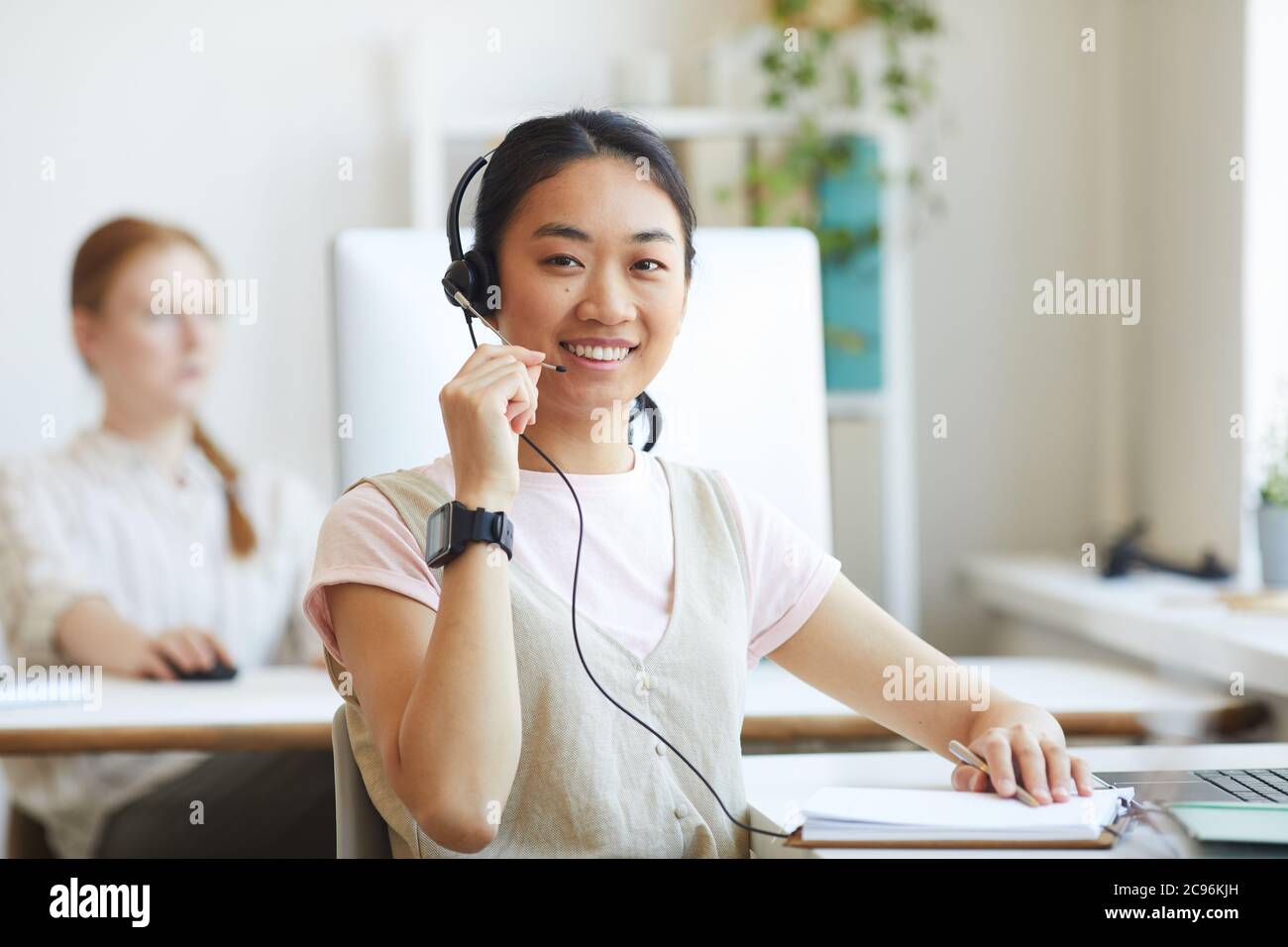 Asiatische Callcenter-Agent trägt Headset lächelnd an der Kamera arbeitet sie in der Kundenbetreuung Stockfoto