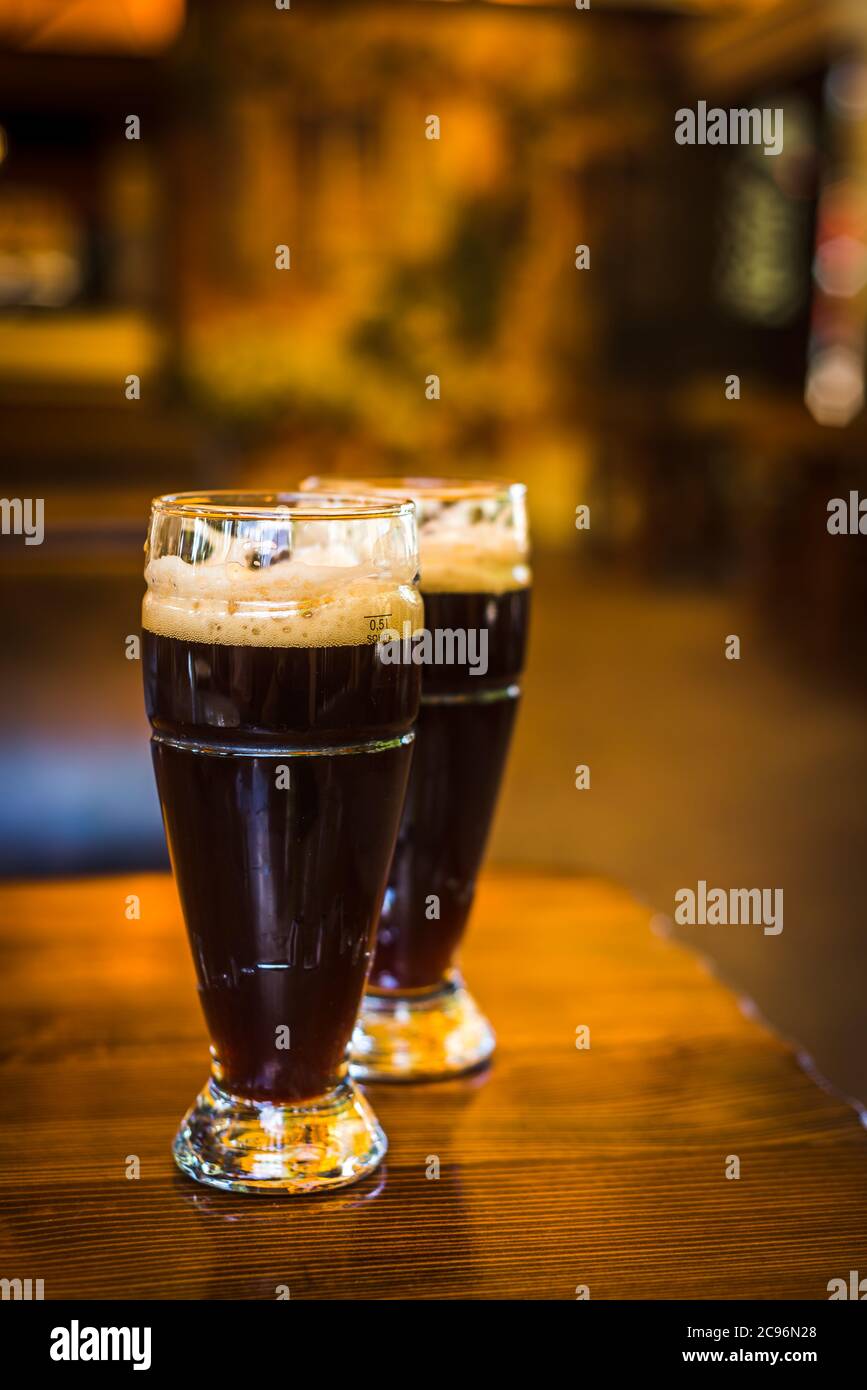 Glas mit dunklen Biersorten auf einer Holzbar. Gläser mit verschiedenen Arten von Fassbier in einem Pub Stockfoto