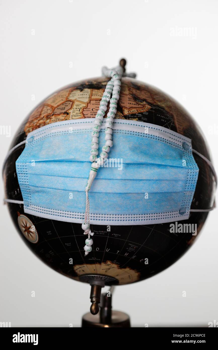 Epidémie de coronavirus ( covid-19). Pandémie mondiale. Chapelet musulman et mappemonde avec masque chirurgical. Frankreich. Stockfoto