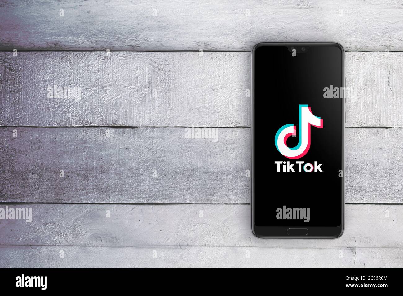 TikTok-App auf einem Smartphone. Weißer Holztisch mit leerem Platz für den Inhalt des Editors. Top-Down-Schuss. Stockfoto