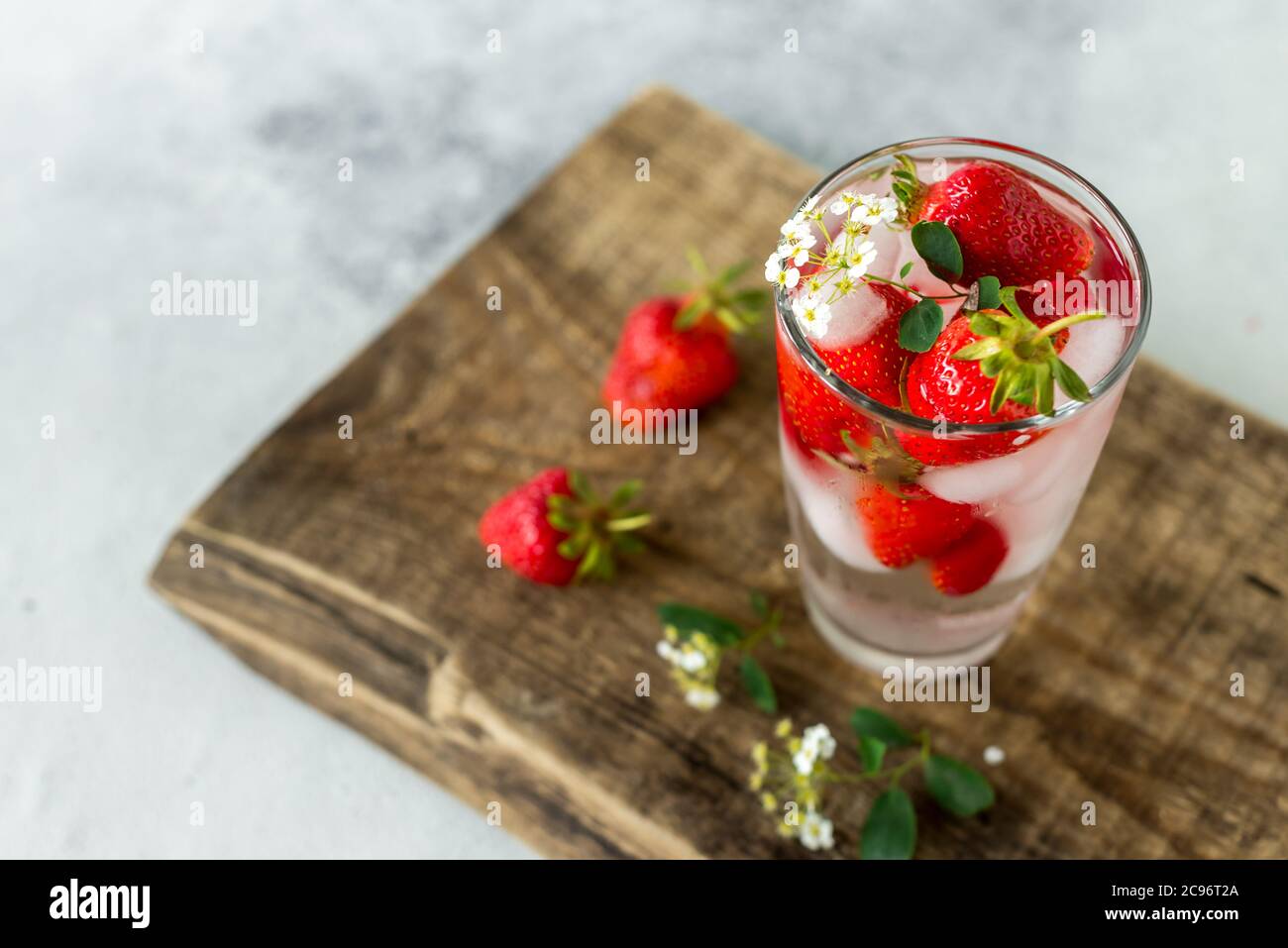 Glas mit einem im Sommer gekühlten klaren kohlensäurehaltigen Getränk, Eis und Erdbeeren. Erfrischende Kühle Stockfoto