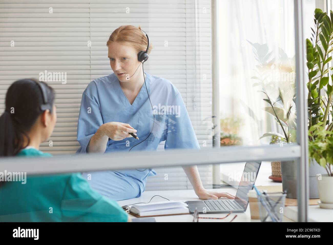 Zwei Kollegen im Kopfhörer sprechen während ihrer Arbeit im medizinischen Call Center miteinander Stockfoto