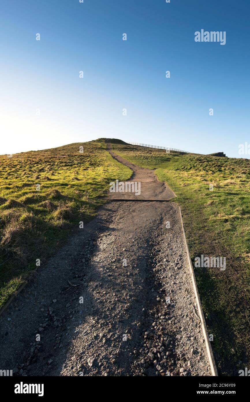 Ein Fußweg, der bis zu den Überresten eines runden Barrows aus der frühen Bronze- Zeit auf dem Gipfel des Porth Island Trevelgue Head in Newquay in Cornwall führt. Stockfoto