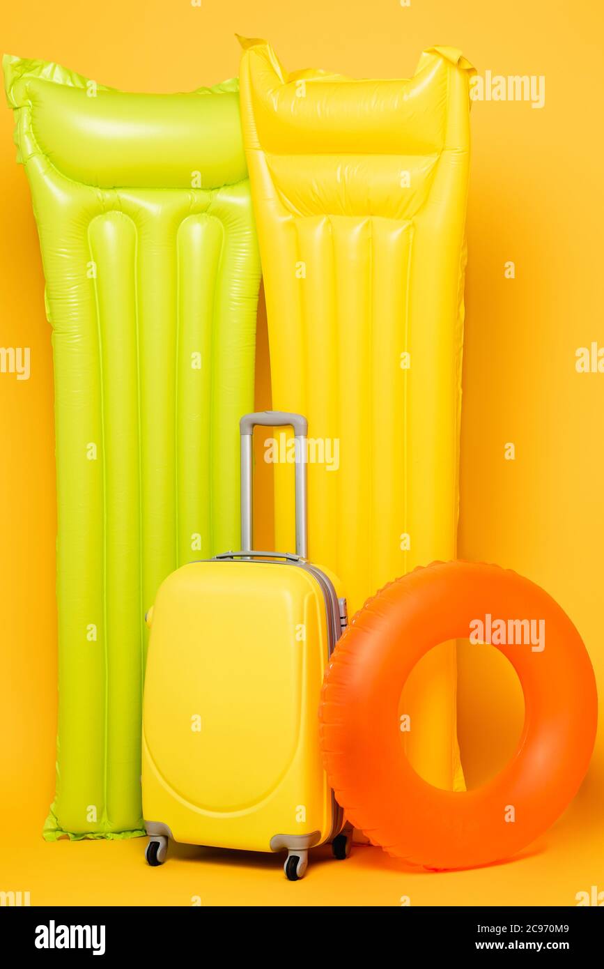Reisetasche mit Pool schwimmt auf gelbem Hintergrund Stockfoto