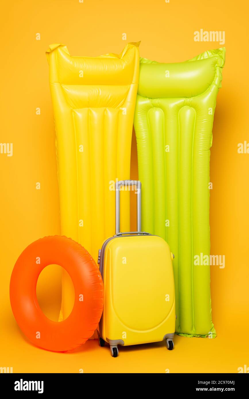 Reisetasche mit Pool schwimmt auf gelbem Hintergrund Stockfoto