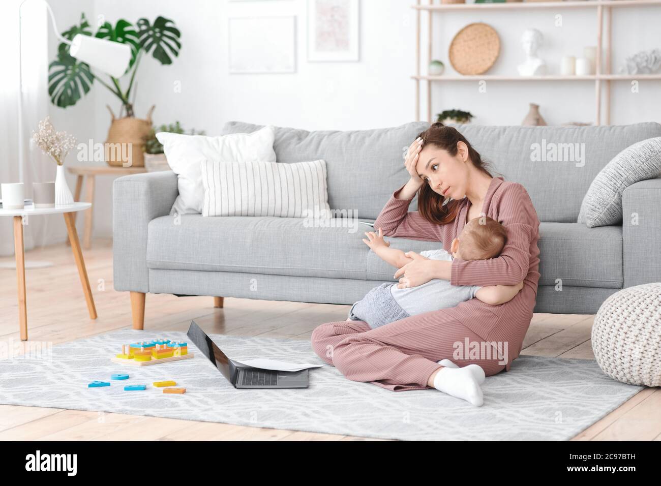 Erschöpfung Der Mutterschaft. Müde Mutter stillen Baby und arbeiten auf Laptop zu Hause Stockfoto