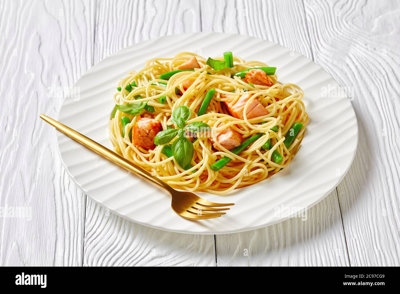 Wild alaska Lachs Pasta mit italienischen Spaghetti, grünen Bohnen und Knoblauchbutter Sauce mit frischem Basilikum auf einem weißen Teller mit Gabel auf einem Whit serviert Stockfoto