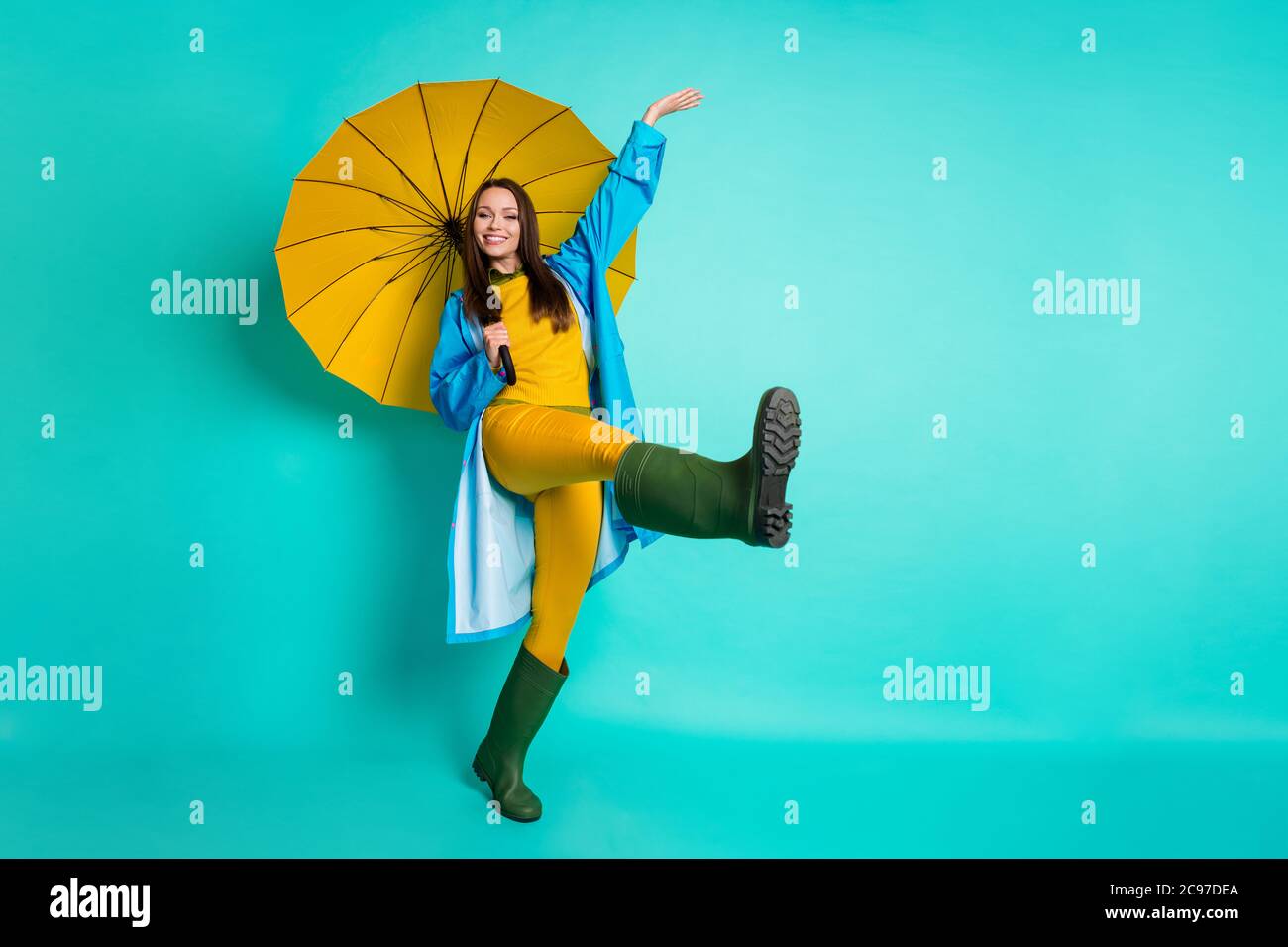 Ganzkörper-Profil-Foto der attraktiven Dame gute Laune regen Gestoppt gehen  Haube Kopf Pfützen halten große gelbe Regenschirm tragen Regenmantel  Pullover Hose Gummi Stockfotografie - Alamy