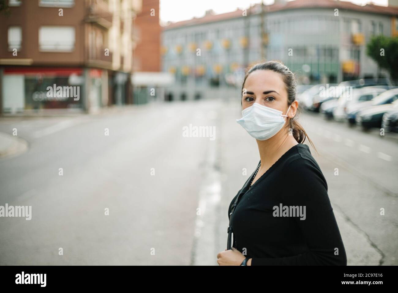 Junge Frau in medizinischen Gesichtsmaske für Coronavirus Prävention auf der Straße Stockfoto