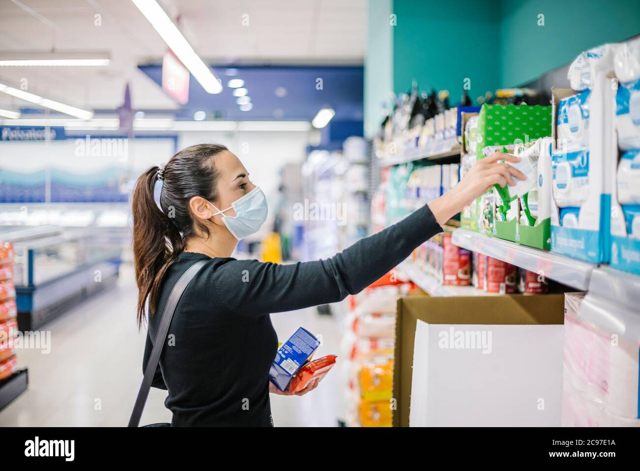 Junge Frau in Gesichtsmaske Einkaufen im Supermarkt während Coronavirus Ausbruch Stockfoto