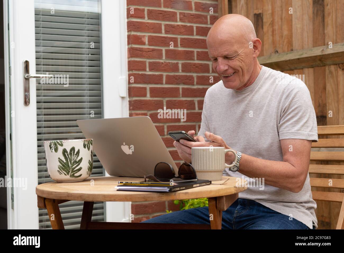 Mann mit Laptop und Handy im Garten Stockfoto