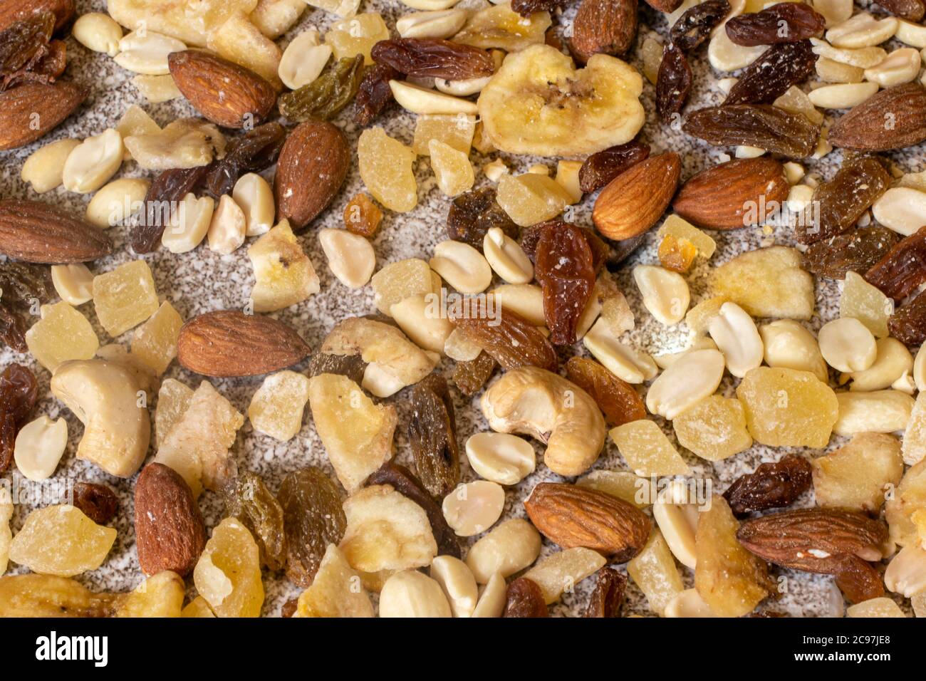 Mischung aus Nüssen und getrockneten Früchten auf einem steingrauen Hintergrund. Erdnüsse, kandierte Ananas, Rosinen, getrocknete Bananen, Feigen, Mandeln. Stockfoto