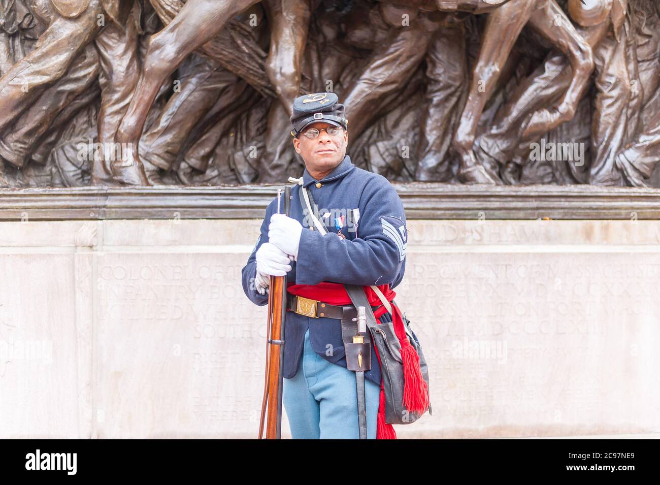 Ein Mitglied der 54. Reenactors-Gruppe des Massachusetts Regiment, das vor Augustus Saint-Gaudens hochreliefarmem Bronzestandmal auf Boston Common T posiert Stockfoto