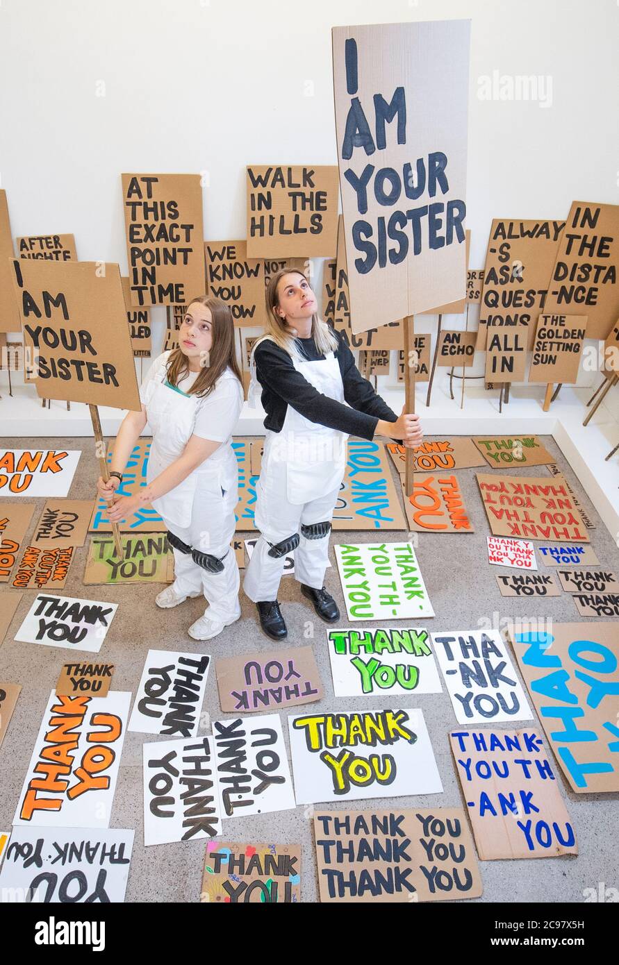 Mirin Cowey (links) und ihre Schwester Beth Cowey (rechts) vom Orbit Youth Council, die dem Künstler Peter Liversidge assistierten, betreiben ein Sign Painting Studio, in dem Kunstwerke zum Mitnehmen im Jupiter Artland in Edinburgh gemalt werden. Die Performance ist Teil von 'Happenings', einer Veranstaltungsreihe, die vom Werk des spätamerikanischen Avantgarde-Künstlers Allan Kaprow (1927-2006) inspiriert ist. Stockfoto