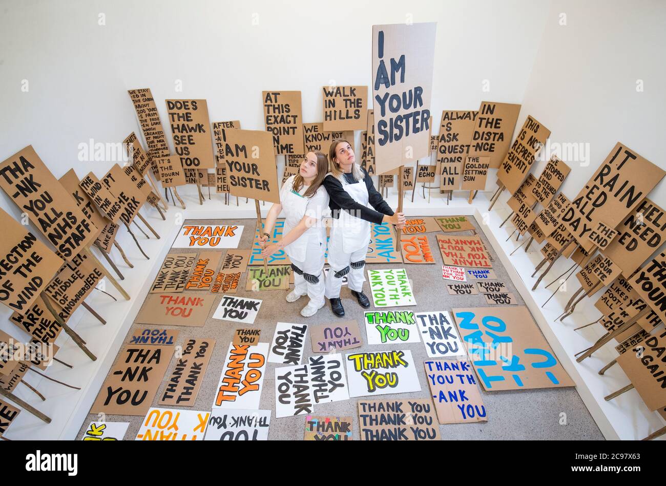 Mirin Cowey (links) und ihre Schwester Beth Cowey (rechts) vom Orbit Youth Council, die dem Künstler Peter Liversidge assistierten, betreiben ein Sign Painting Studio, in dem Kunstwerke zum Mitnehmen im Jupiter Artland in Edinburgh gemalt werden. Die Performance ist Teil von 'Happenings', einer Veranstaltungsreihe, die vom Werk des spätamerikanischen Avantgarde-Künstlers Allan Kaprow (1927-2006) inspiriert ist. Stockfoto