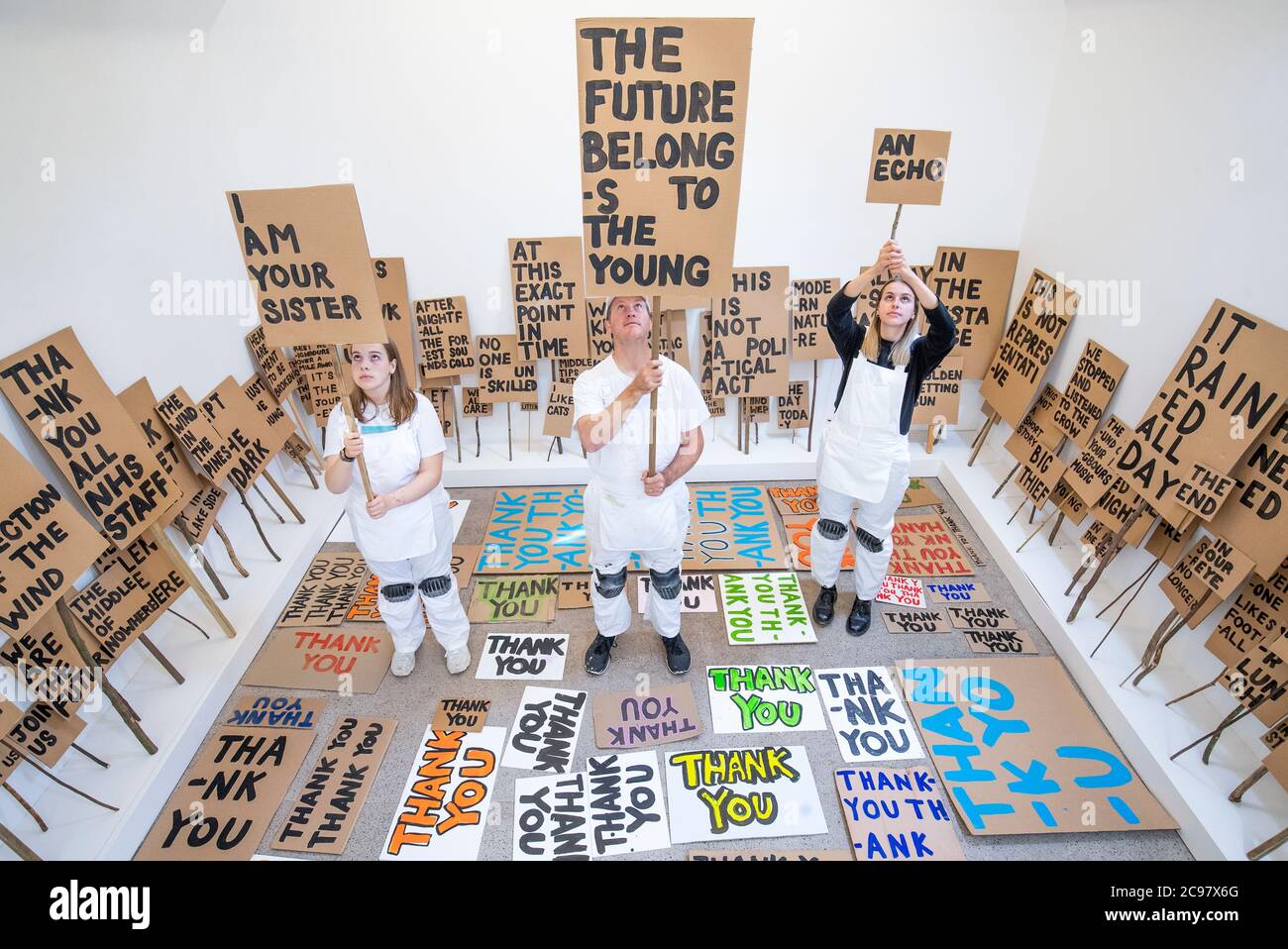 Künstler Peter Liversidge, zusammen mit Mirin Cowey (links) und ihrer Schwester Beth Cowey vom Orbit Youth Council, die ein Sign Painting Studio betreiben, in dem Kunstwerke auf Wunsch zum Mitnehmen im Jupiter Artland, Edinburgh gemalt werden. Die Performance ist Teil von 'Happenings', einer Veranstaltungsreihe, die vom Werk des spätamerikanischen Avantgarde-Künstlers Allan Kaprow (1927-2006) inspiriert ist. Stockfoto