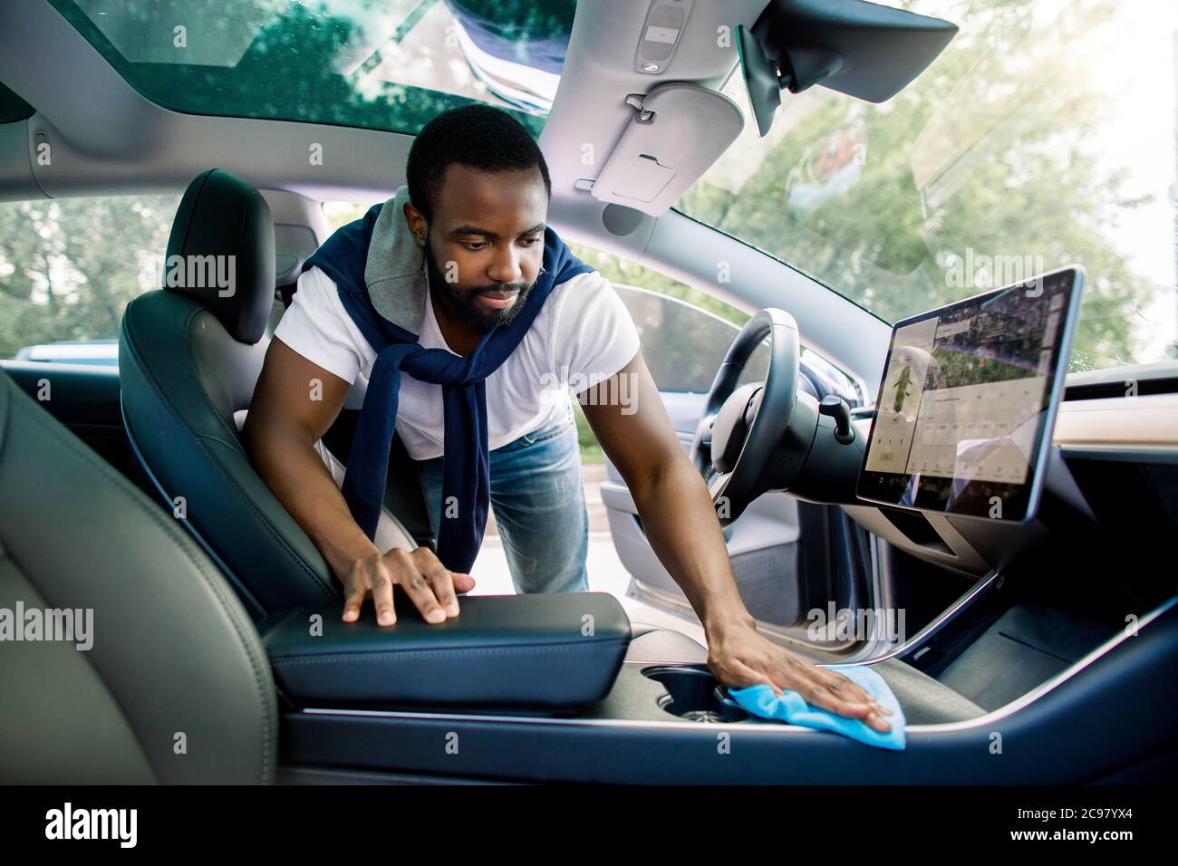 Reinigungsservice, Autoinnenreinigung. Schöner afrikanischer Mann in  legerer Kleidung, wäscht ein Auto Interieur mit Mikrofaser Tuch in seinem  modernen Elektroauto Stockfotografie - Alamy