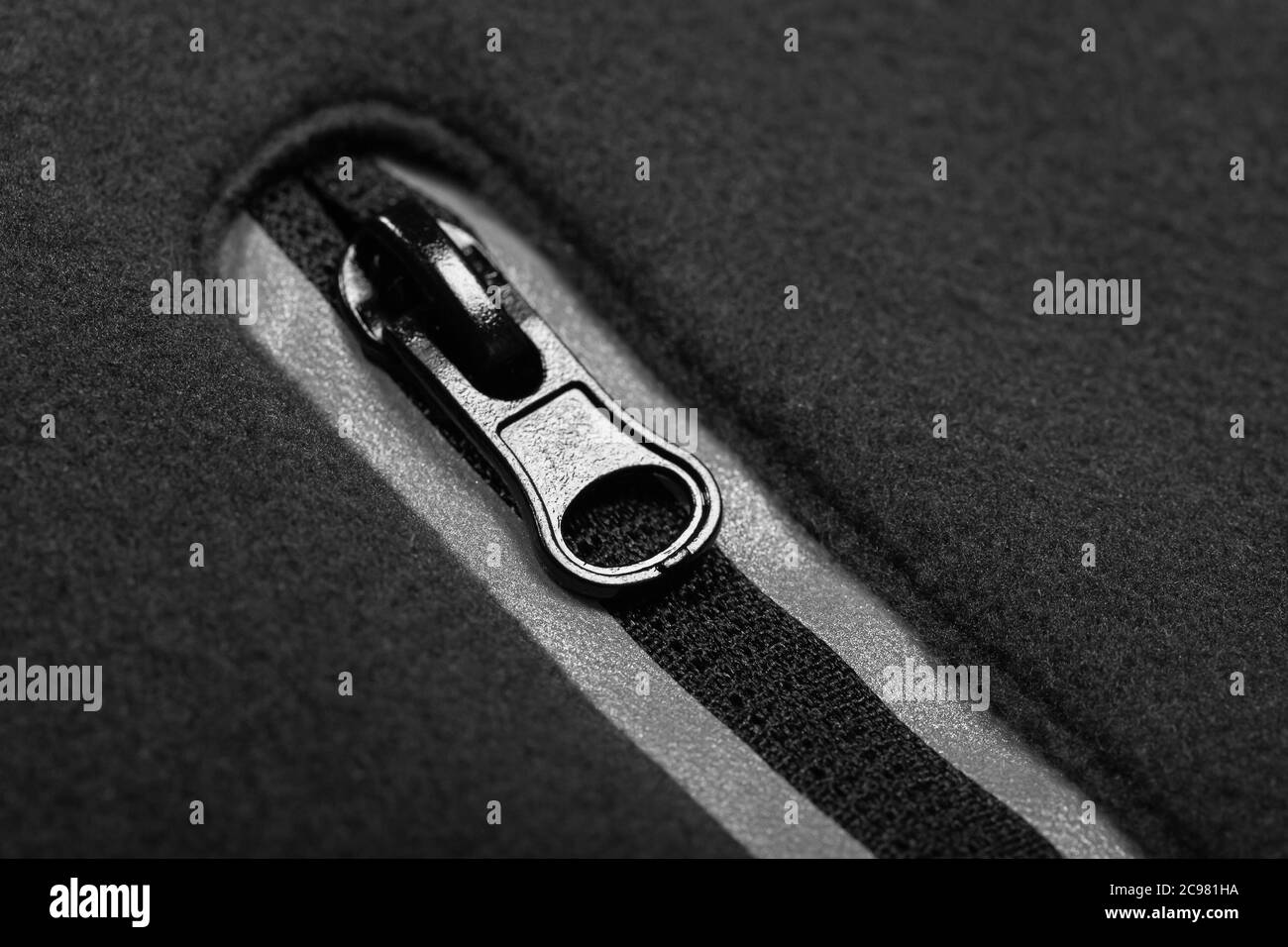 Reißverschluss mit Reflektoren aus grauem Fleece-Jackentasche, Makro-Foto Stockfoto