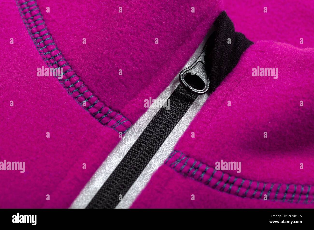 Reißverschluss mit Reflektor einer rosa Fleecejacke, Nahaufnahme Stockfoto