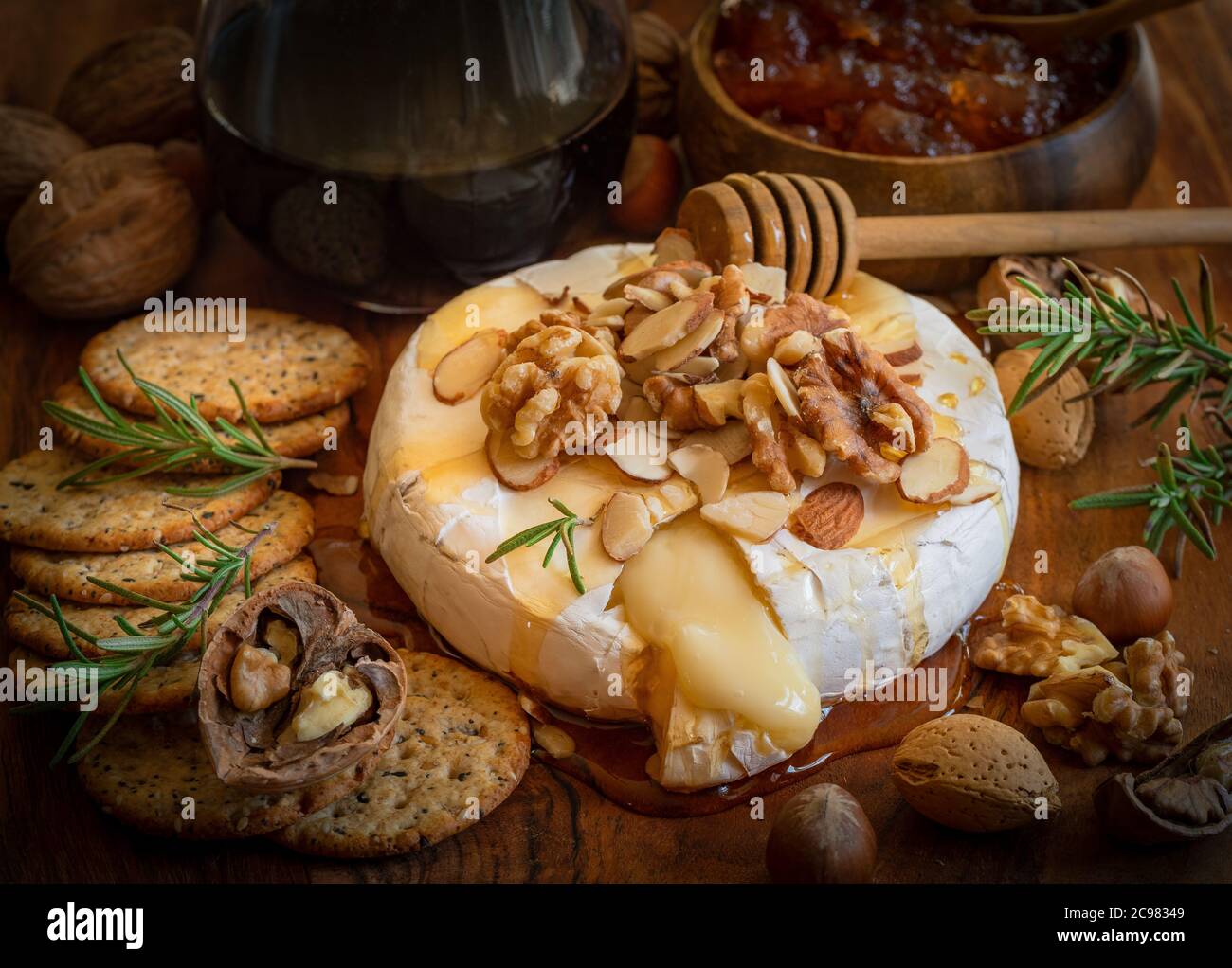 Käseplatte für eine Vorspeise serviert: Gebackene Brie, Cracker, Marmelade und Nüsse. Stockfoto
