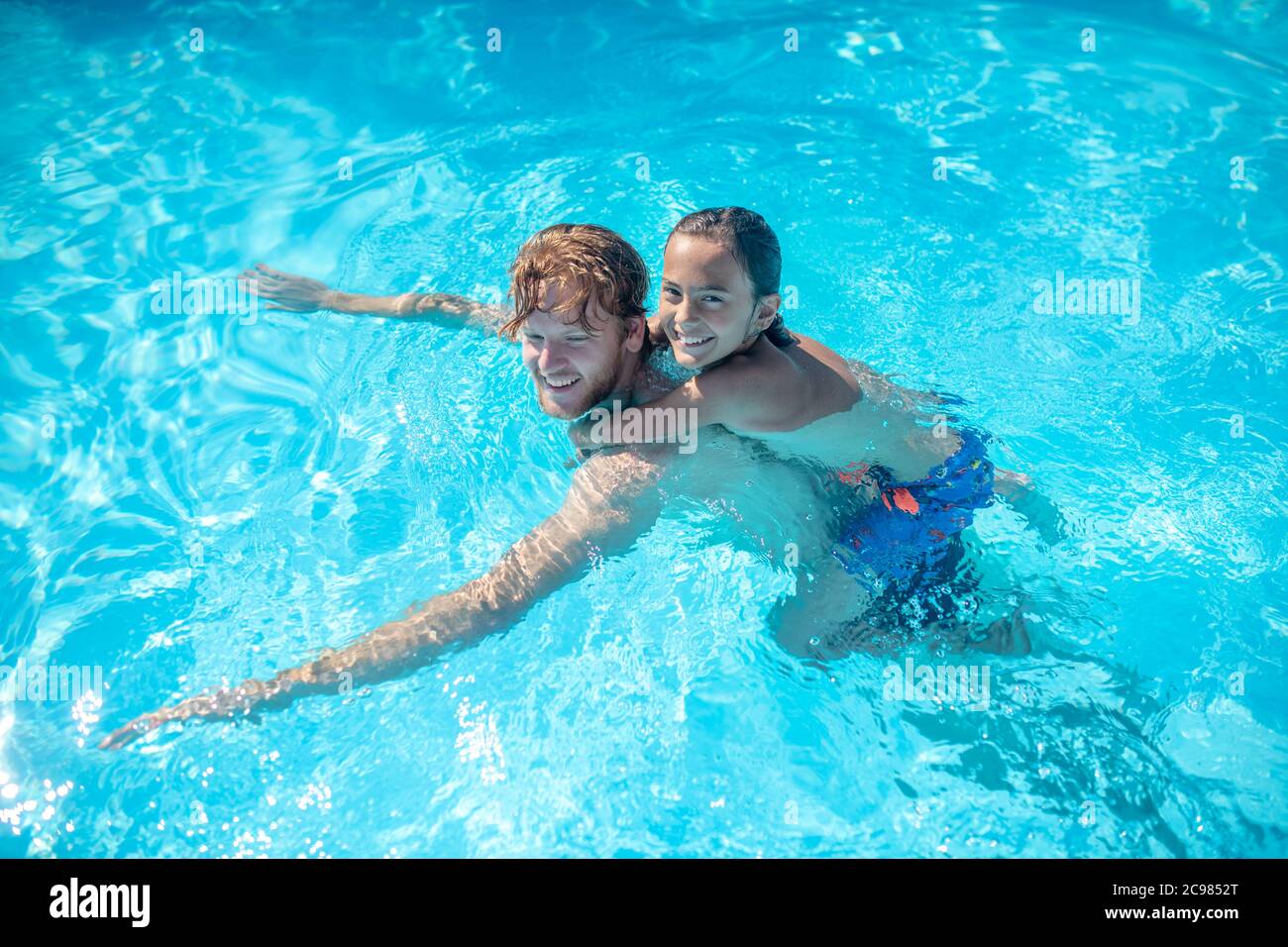 Papa mit Sohn auf dem Rücken schwimmen im Pool Stockfoto