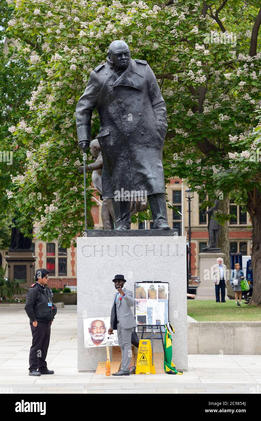 London, England, Großbritannien. Lone Windrush Demonstrator streiten mit einem Heritage Warden auf dem Parliament Square über seine Aktivitäten durch die Churchill Statue Stockfoto