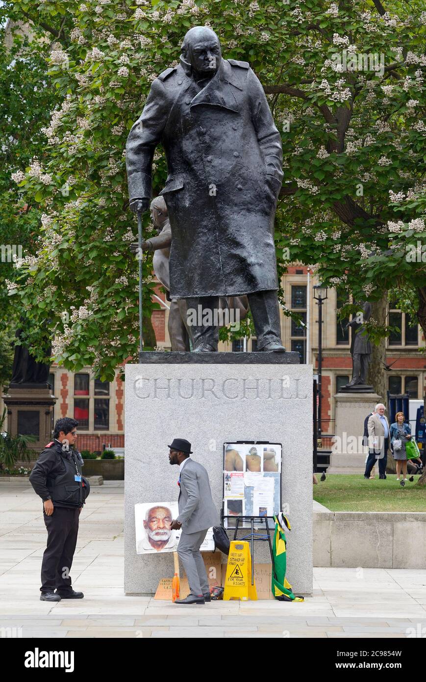 London, England, Großbritannien. Lone Windrush Demonstrator streiten mit einem Heritage Warden auf dem Parliament Square über seine Aktivitäten durch die Churchill Statue Stockfoto
