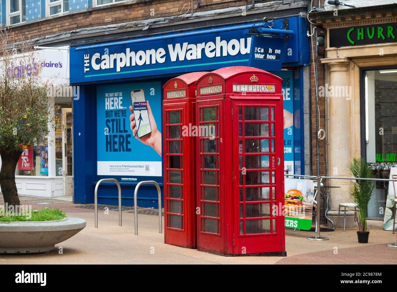 Ursprüngliche alte rote Telefonzellen, die von BT betrieben werden, stehen vor einem Ladengeschäft für Autotelefone, das gerade aufgrund der Entwicklung in der Telefonkommunikationsbranche geschlossen wurde. Bournemouth England (120) Stockfoto