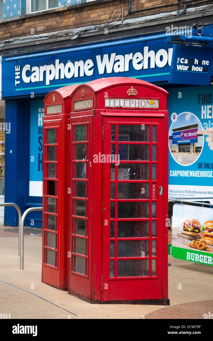 Ursprüngliche alte rote Telefonzellen, die von BT betrieben werden, stehen vor einem Ladengeschäft für Autotelefone, das gerade aufgrund der Entwicklung in der Telefonkommunikationsbranche geschlossen wurde. Bournemouth England (120) Stockfoto