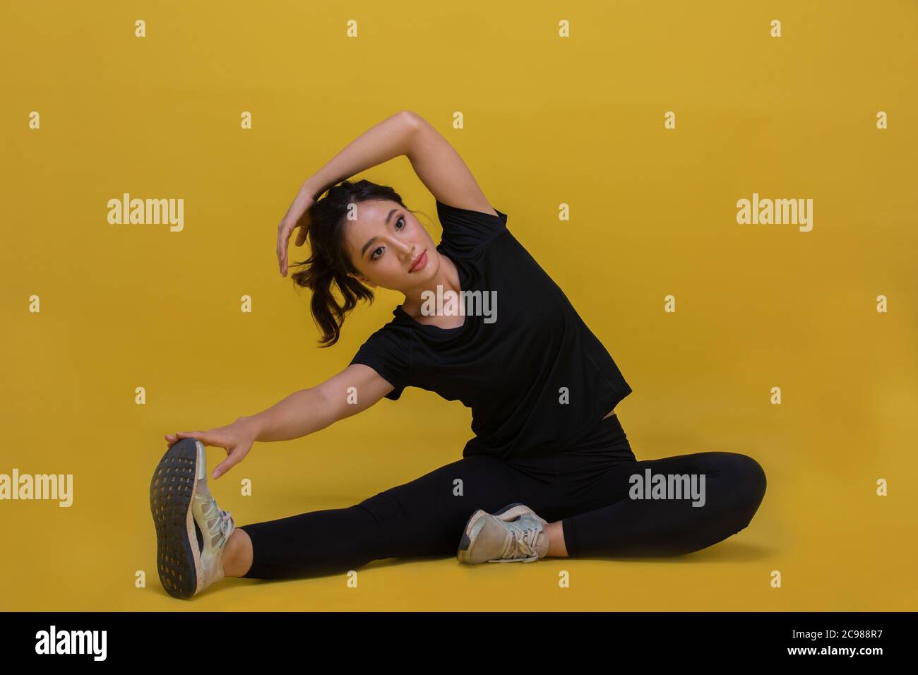 Lächeln glücklich schöne Porträt junge asiatische Frau Stretching Übung Workout auf gelbem Hintergrund, Fitness Sport Mädchen Aerobic und gesundes Konzept. Stockfoto