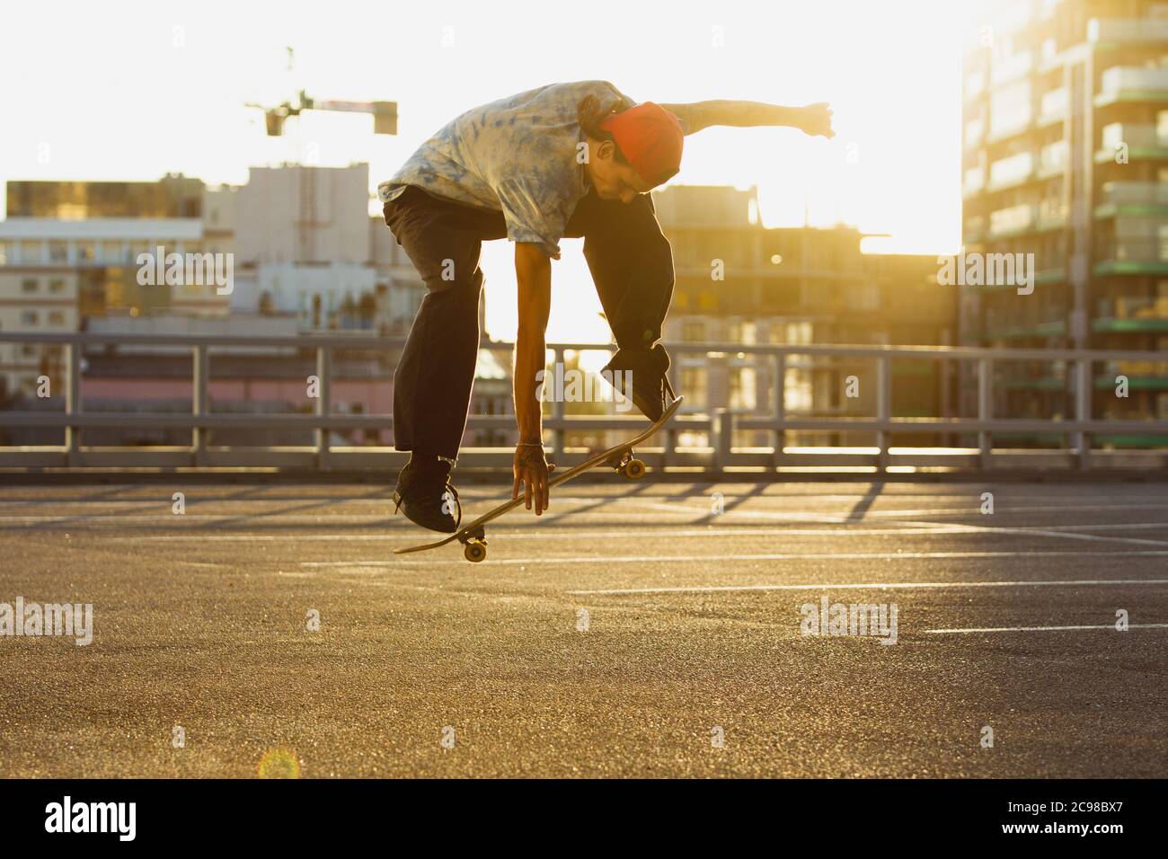 Skateboarder bei der Sommersonne auf der Straße der Stadt. Junger Mann in Turnschuhen und Cap Reiten und Skateboarding auf dem Asphalt. Konzept von Freizeitaktivitäten, Sport, Extremsport, Hobby und Bewegung. Stockfoto