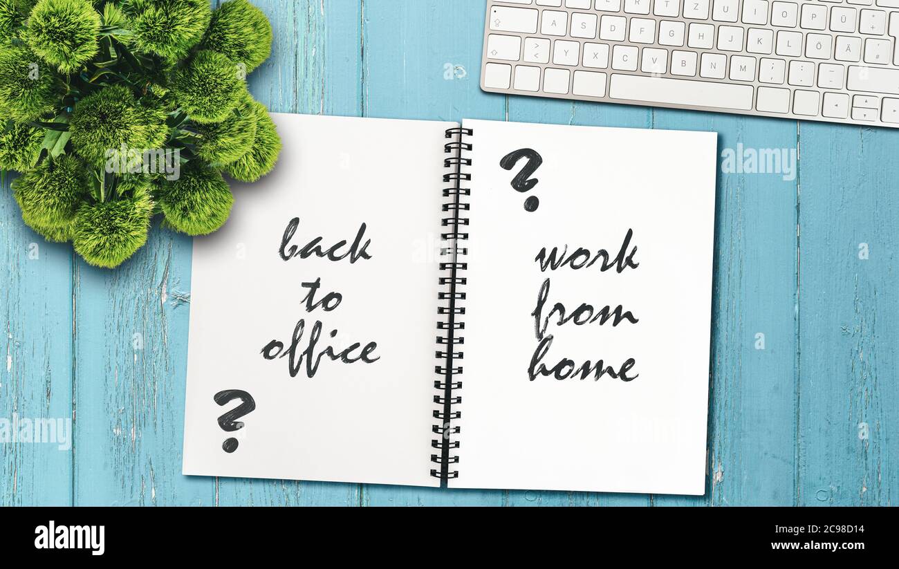 Arbeiten Sie weiter von zu Hause oder gehen Sie zurück zum Bürokonzept mit Notizblock und Computertastatur auf rustikalem Holztisch Stockfoto