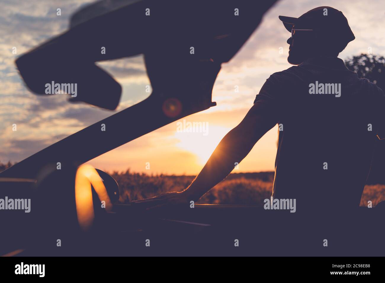 Kaukasische Männer in seinen 40er Jahren genießen szenischen Moment während Golden Hour Sonnenuntergang. Fahrt Mit Dem Cabrio. Violett Matt Farbe Gegratet. Stockfoto