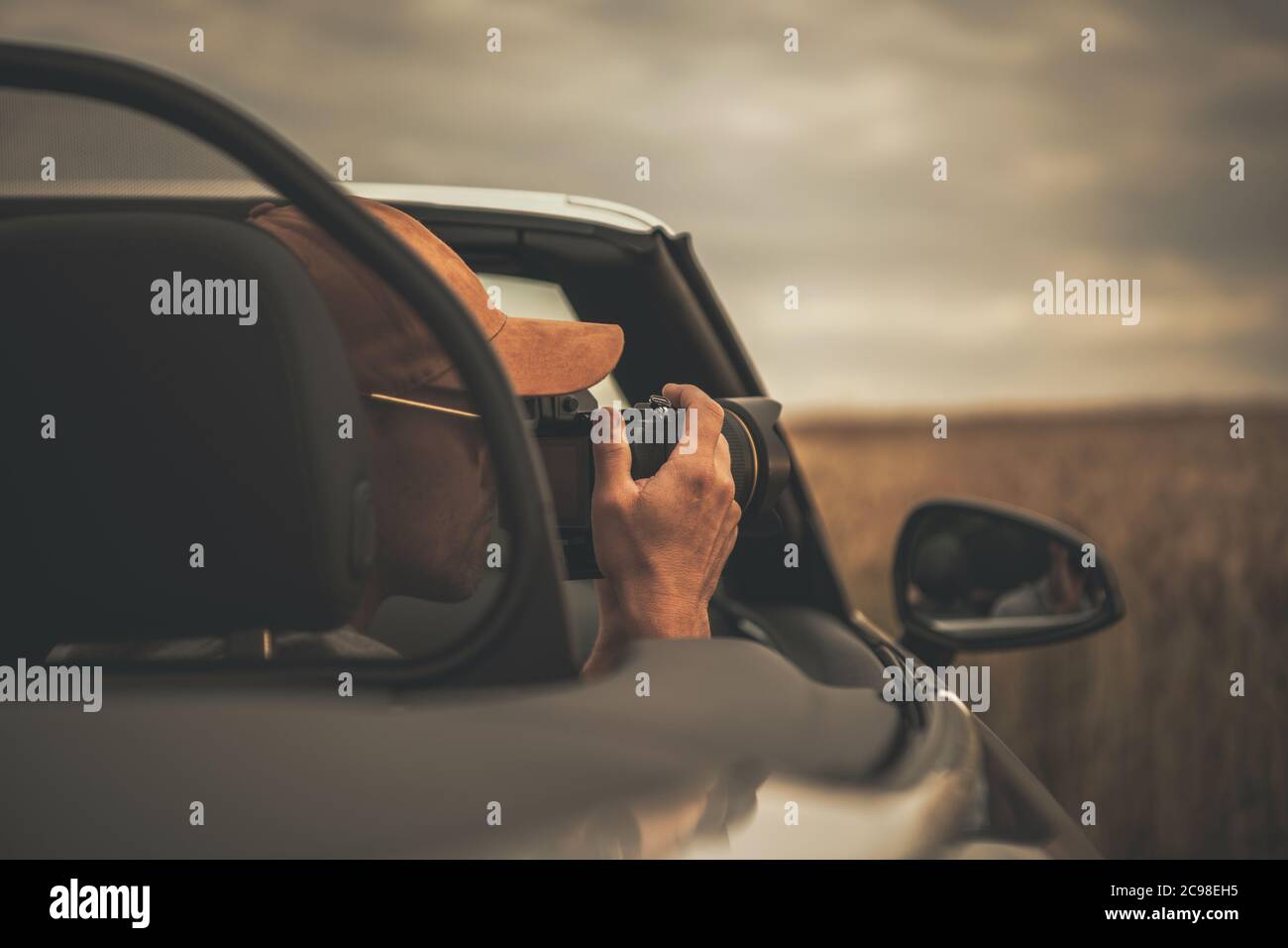 Kaukasischer Tourist in seinen 40er Jahren, der während der Fahrt Bilder von seinem Cabrio-Fahrzeug nimmt. Thema Reise- und Tourismusbranche. Stockfoto