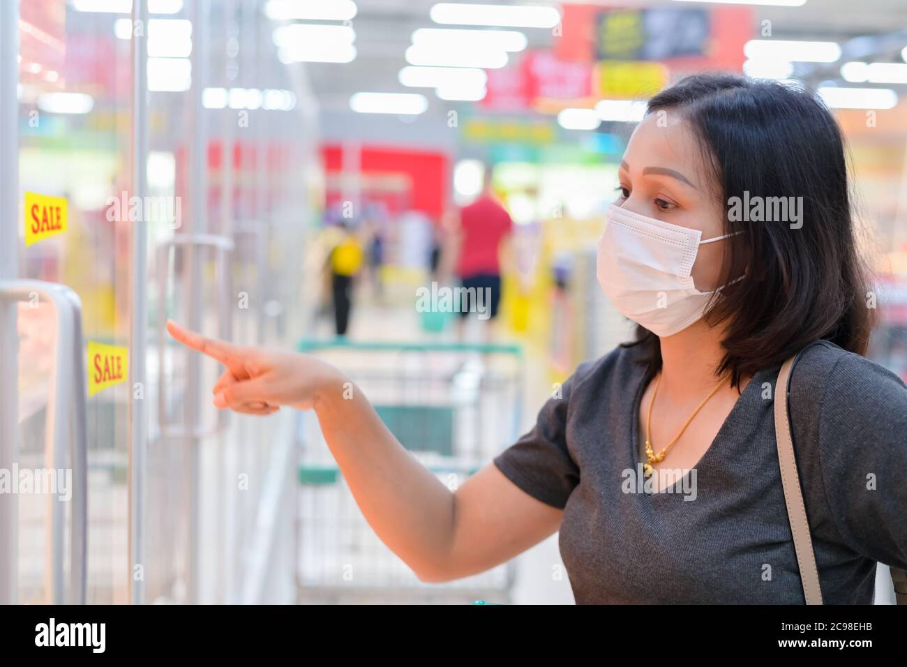 Asiatische Frau trägt Einweg medizinische Maske Einkauf im Supermarkt während Coronavirus-Epidemie Stockfoto