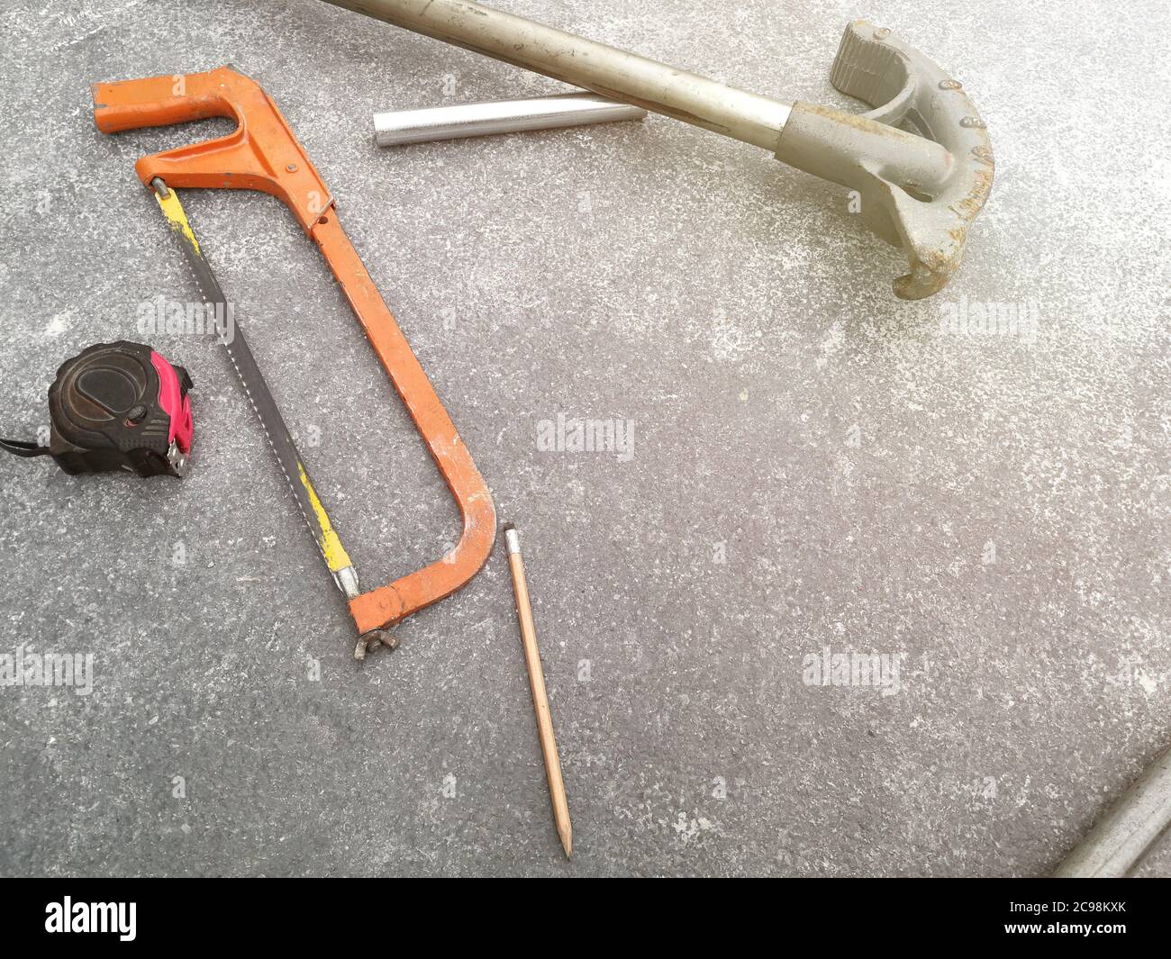 Maßband und Hacksäge auf dem Boden auf der Baustelle Stockfoto