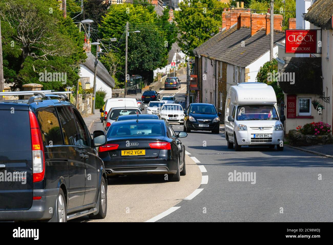 Chidock, Dorset, Großbritannien. Juli 2020. Die A35 auf dem Chideock Hill im ländlichen Dorf Chideock in Dorset hat laut Friends of the Earth-Analyse die schlechtesten Stickstoffdioxidwerte im Land, die durch den langsamen Urlaubsverkehr verursacht werden. Starker Verkehr, der langsam durch das Dorf zieht. Bild: Graham Hunt/Alamy Live News Stockfoto