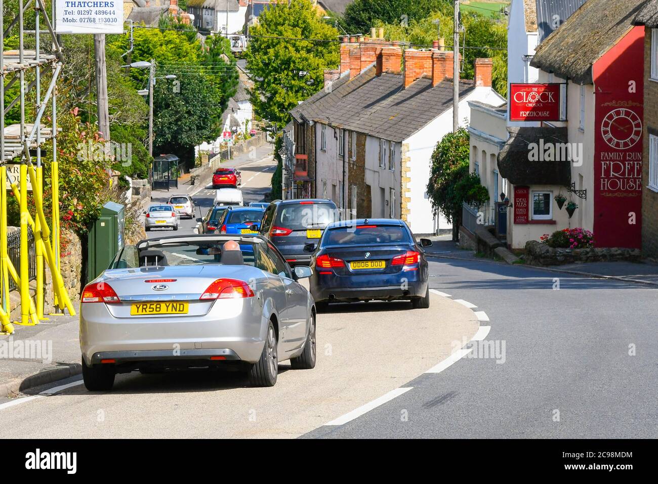 Chidock, Dorset, Großbritannien. Juli 2020. Die A35 auf dem Chideock Hill im ländlichen Dorf Chideock in Dorset hat laut Friends of the Earth-Analyse die schlechtesten Stickstoffdioxidwerte im Land, die durch den langsamen Urlaubsverkehr verursacht werden. Starker Verkehr, der langsam durch das Dorf zieht. Bild: Graham Hunt/Alamy Live News Stockfoto