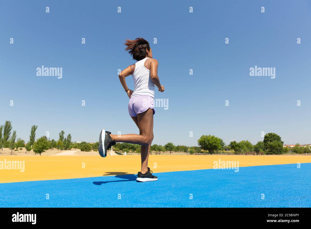 Rückseite einer Brünette Frau sprintet auf einer athletischen Strecke. Leerzeichen für Text. Stockfoto