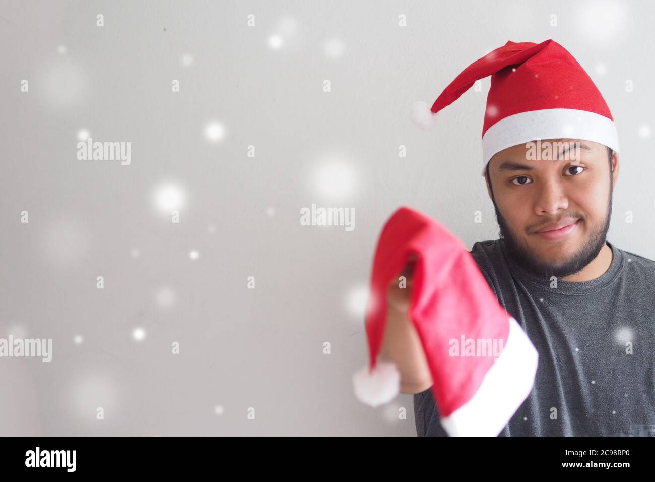 Mann trägt einen Weihnachtsmann Hut gibt Weihnachtsmann Hut für Sie mit Snow Scene und Copy Space. Stockfoto